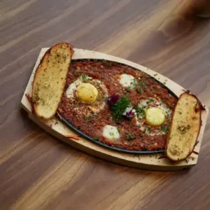 Plate of Shakshuka with poached eggs, tomatoes, peppers, and herbs, served fresh at a café