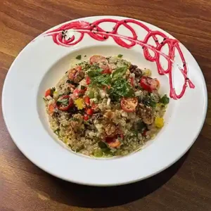 Quinoa salad with fresh vegetables and grilled chicken, served in a bowl as a healthy café-style meal.
