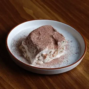 Italian Tiramisu dessert with layers of mascarpone and coffee-soaked ladyfingers, served fresh in café style.