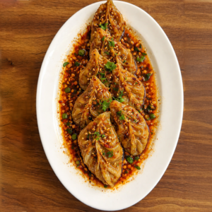 Momos tossed in garlic chili oil with spicy sauce served fresh at Avayacafe