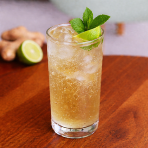 Glass of Ginger Ale Cooler with lime slice, mint, and sparkling soda served at Avayacafe.