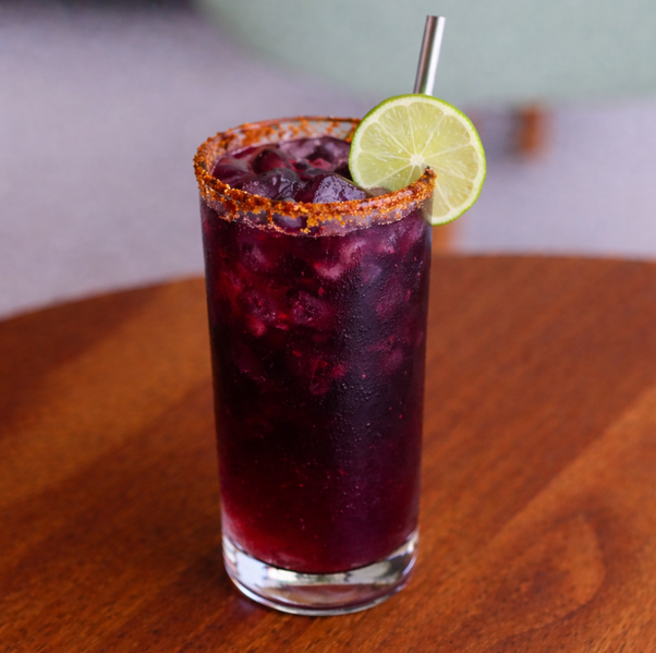 Glass of Jamun Kala Khatta drink with ice and spice garnish served at Avayacafe.